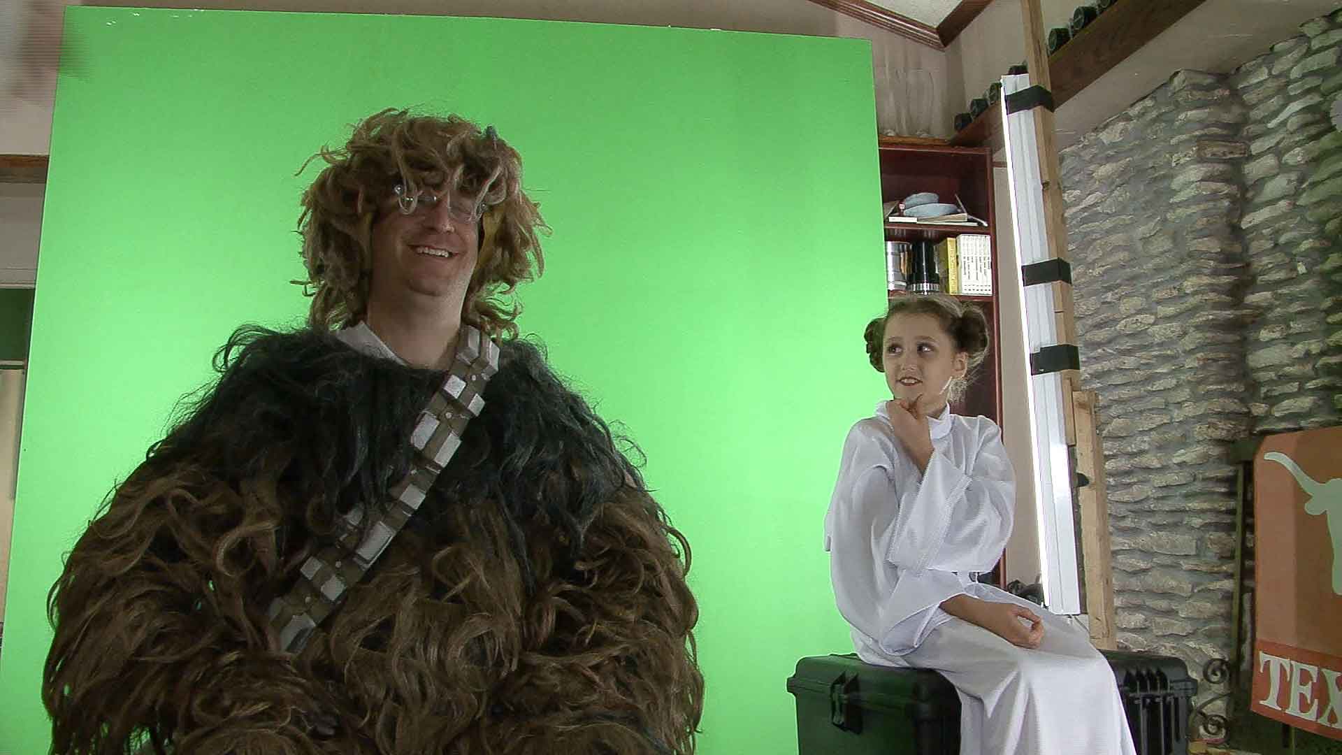 Christopher as Chewbacca in front of a green screen next to a kid being Princess Leia looking at him